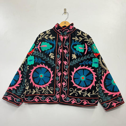 Colorful embroidered jacket on a hanger against a white background