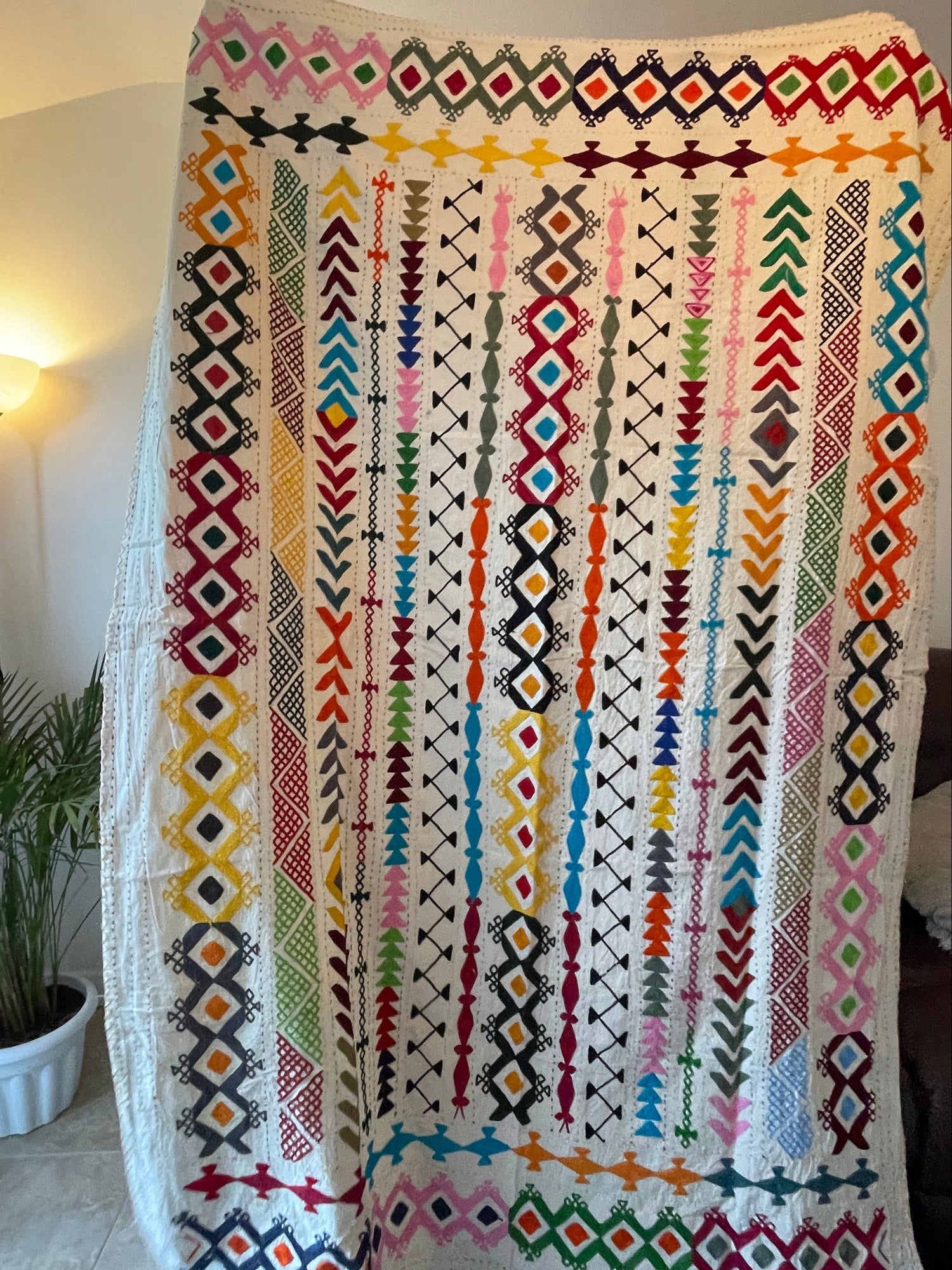 Colorful patterned throw on a white surface with a blurred background