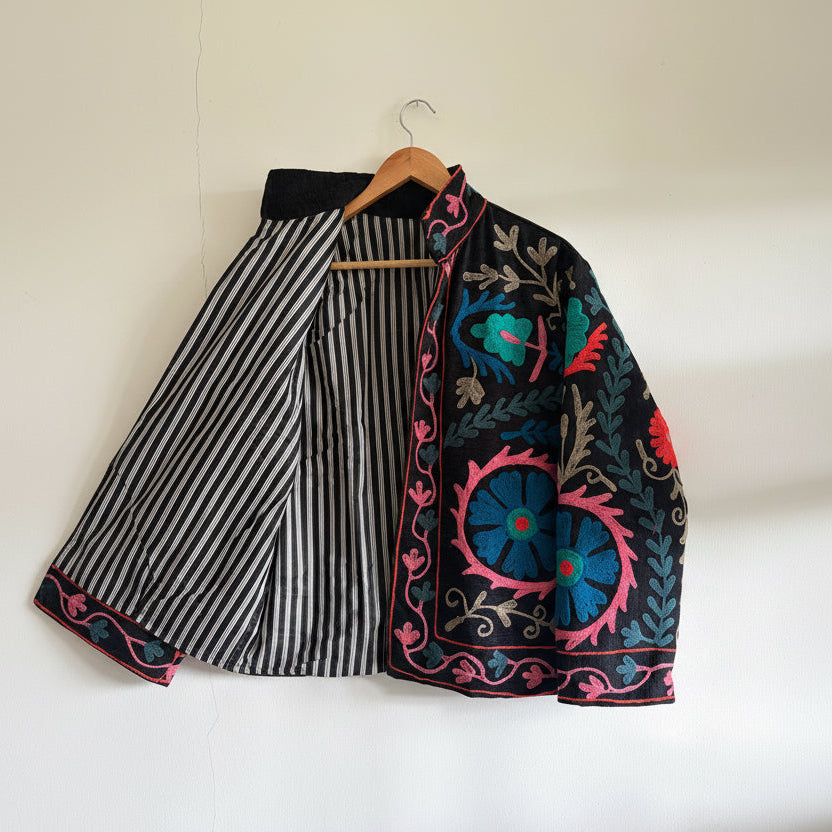 Embroidered fabric with floral patterns on a wooden hanger against a white background