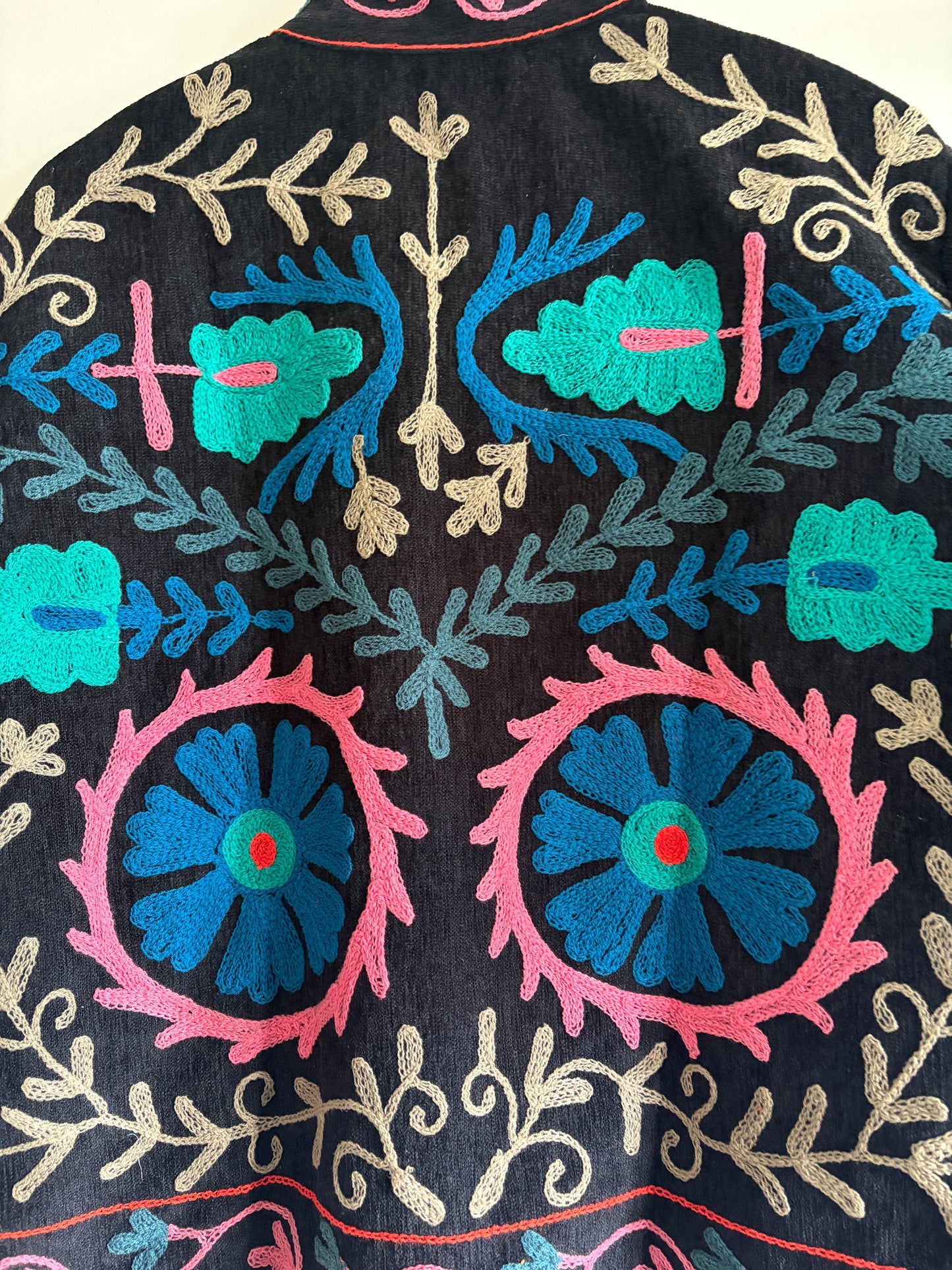 Close-up of embroidered fabric with floral and geometric patterns on a dark background