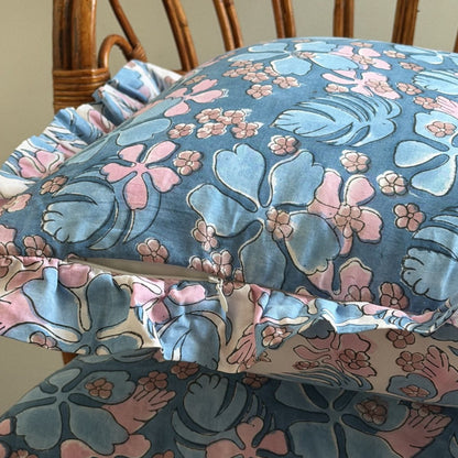 Blue floral pillowcase with pink and light blue tropical flowers and ruffled edges. 