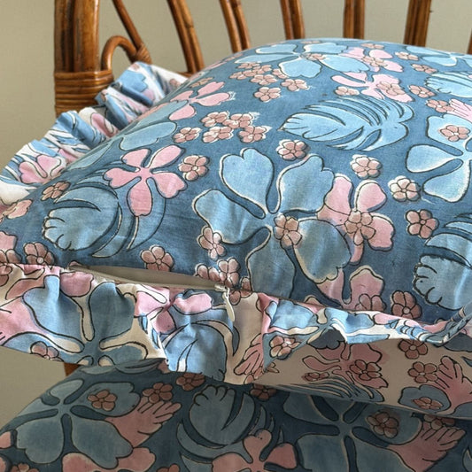 Blue floral pillowcase with pink and light blue tropical flowers and ruffled edges. 